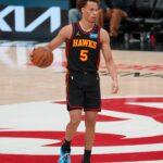 Dyson Daniels #5 of the Atlanta Hawks dribbles a basketball with his right hand while looking toward the basket. He is wearing the team's black Statement Edition uniform and bright blue sneakers.