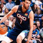 Chet Holmgren #7 of the Oklahoma City Thunder dribbles a basketball with his right hand while driving toward the basket. He is wearing the team's dark blue City Edition uniform.