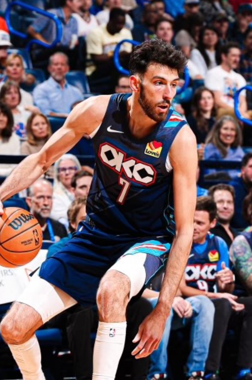 Chet Holmgren #7 of the Oklahoma City Thunder dribbles a basketball with his right hand while driving toward the basket. He is wearing the team's dark blue City Edition uniform.