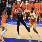 Miami Heat guard Tyler Herro (14) makes a pass while being defended by Charlotte Hornets players during an NBA game at Spectrum Center.