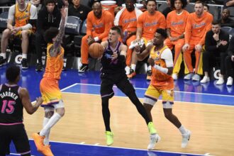 Miami Heat guard Tyler Herro (14) makes a pass while being defended by Charlotte Hornets players during an NBA game at Spectrum Center.