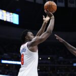 New York Knicks forward OG Anunoby (8) is captured from a side-view angle in mid-air, releasing a jump shot