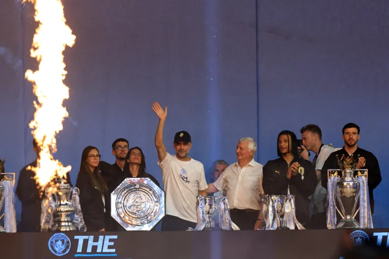Guardiola waves to fans as players pose next to all the trophies won over the length of Pep Guardiola’s decade-long career at Man City